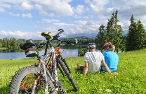 two men sitting in the grass next to a bike at Hotel Natur-Landhaus Krone in Maierhöfen
