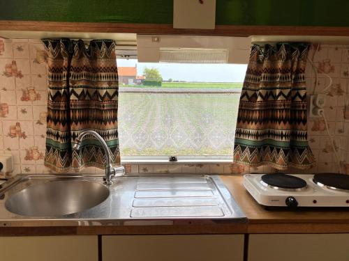 a kitchen counter with a sink and a window at Retro stekje in Nieuwerkerk