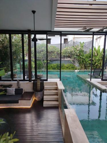 a house with a swimming pool with glass walls at Villa Australis in Kerobokan