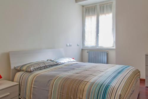 1 dormitorio con 1 cama con manta a rayas y ventana en So Suite Rome, en Roma