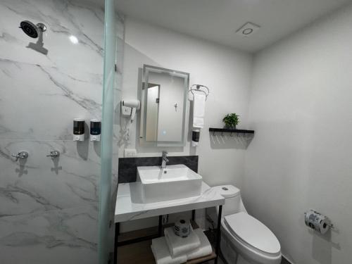 a white bathroom with a sink and a toilet at San Jeronimo Suites in Monterrey