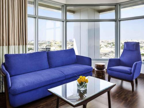 a living room with a blue couch and two chairs at Novotel Jeddah Tahlia in Jeddah
