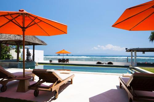 a pool with chairs and umbrellas next to a swimming pool at Villa Kaniksa in Candidasa