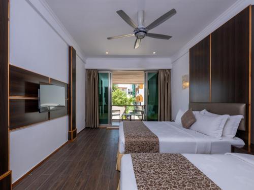 two beds in a hotel room with a ceiling fan at Kaani Village & Spa - Stay 3 Nights and Save 20 Percent on Spa and 10 Percent on Dining Until 31 October 2026 in Maafushi
