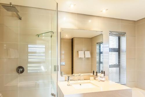 a bathroom with a sink and a shower and a mirror at The Fairway Hotel, Spa & Golf Resort in Johannesburg