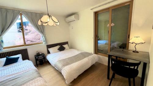 a bedroom with two beds and a desk and a table at Sakura View Nagoya Stay Hub in Nagoya