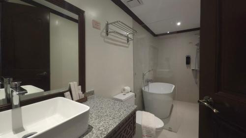 a bathroom with a sink and a toilet and a mirror at Red Coconut Beach Hotel Boracay in Boracay