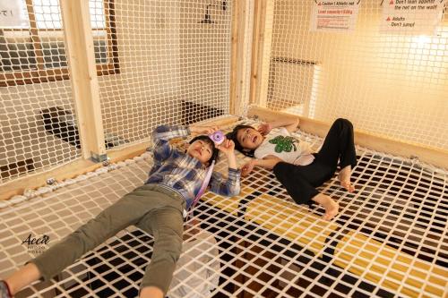 two people laying on top of a bird cage at コテージくつろぎ in Tsuru 
