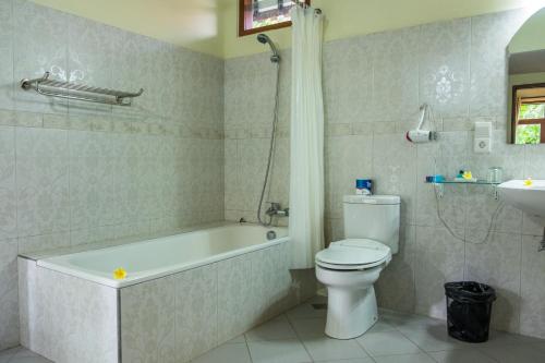 a bathroom with a tub and a toilet and a sink at Taman Surgawi Resort & Spa in Jasri