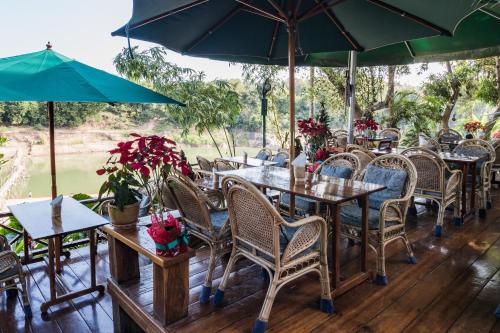 an outdoor restaurant with tables and chairs and umbrellas at Mekong Riverview Hotel in Luang Prabang