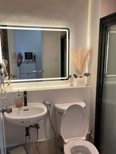 a bathroom with a toilet and a sink and a mirror at Cozyluxe at Pine Suites Tagaytay in Kaybagal