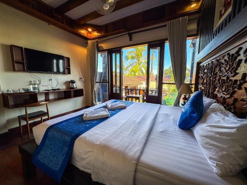 a bedroom with a large bed with a large window at NamKhan Riverside in Luang Prabang