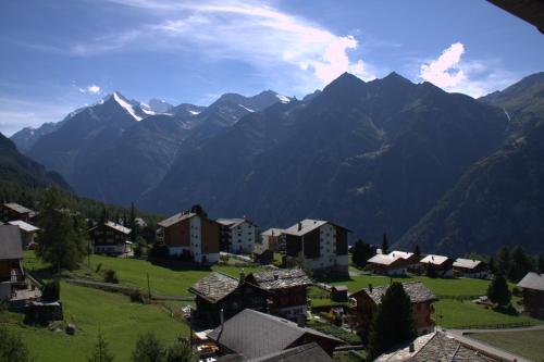 a village in a valley with mountains in the background at Hotel Eden in Grächen