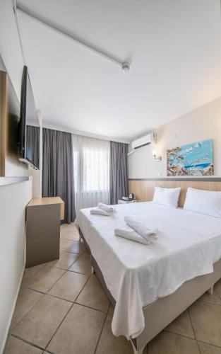 a bedroom with a large bed with white sheets at SUNMARİS CİTY HOTEl in Marmaris