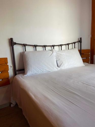 a bedroom with a bed with white sheets and pillows at Two Palm Trees 1 in Adamantas