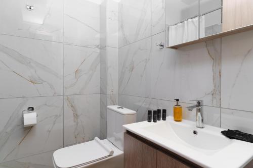 a white bathroom with a toilet and a sink at The Dandy Family Apartments in Syvota