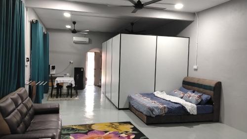 a bedroom with a bed and a couch and a table at Roomstay Ust Omar in Tumpat