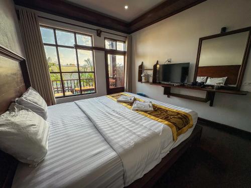 a bedroom with a large bed and a large window at Namkhan Riverside Hotel in Luang Prabang