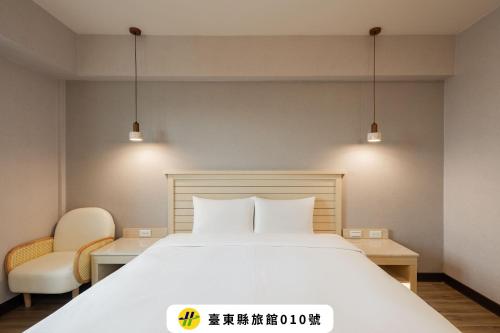 a bedroom with a large white bed and two chairs at Kindness Hotel - Taitung Branch in Taitung City