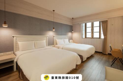 two beds in a hotel room with white sheets at Kindness Hotel - Taitung Branch in Taitung City