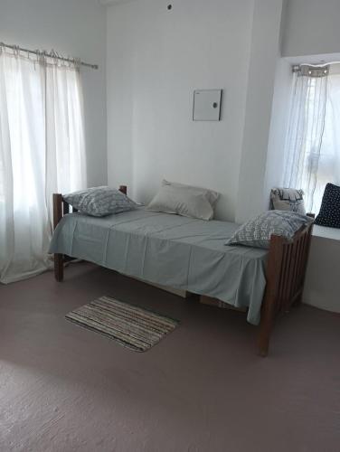 a bed in a white room with two pillows at Casa De Campo in Idukki