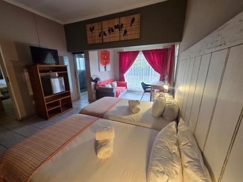 a bedroom with two beds and a living room at Aqua Terra Guest House in Lydenburg