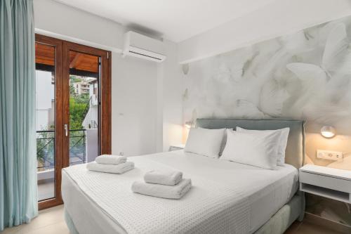 a bedroom with a white bed with towels on it at The Dandy Family Apartments in Syvota