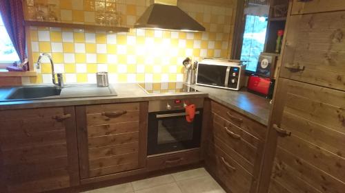 a kitchen with wooden cabinets and a sink and a microwave at Le Solé Bassurois in Basse-sur-le-Rupt