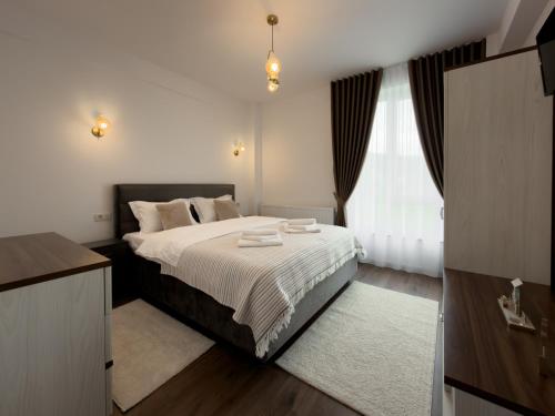 a bedroom with a large bed with white sheets at Bucovina Comfort Apartament in Gura Humorului