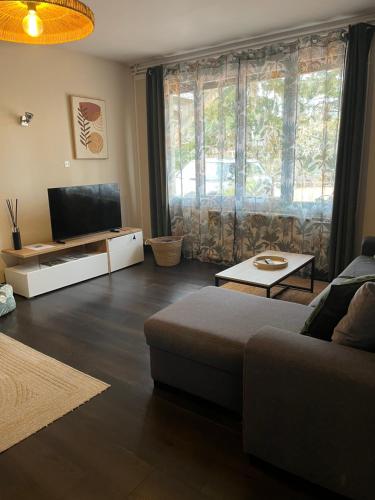 a living room with a couch and a large window at Appartement 4 pers avec jardin & parking-calme-proche Clermont in Royat