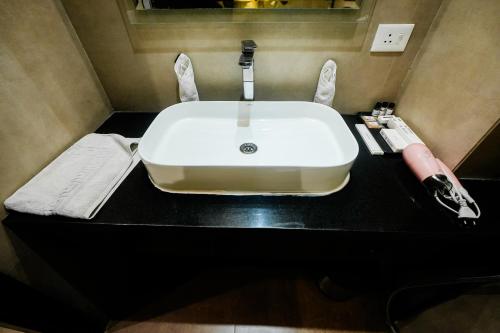 a white sink on a black counter in a bathroom at HOTEL DHAROHAR in Pura Raghunāth