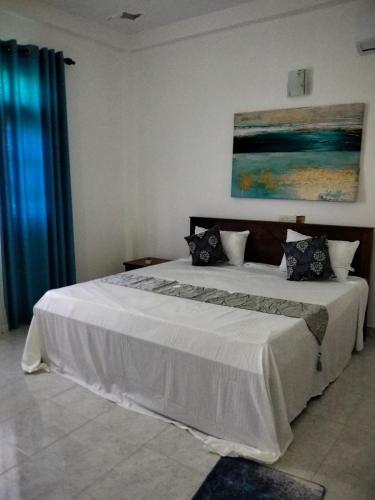 a bedroom with a large white bed and a painting at Peacock Forest Villa in Kosgoda