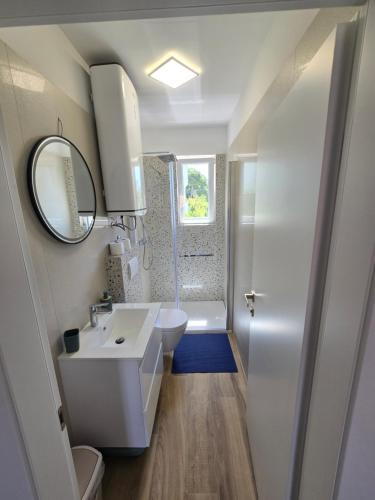 a white bathroom with a sink and a shower at Apartment Tome in Biograd na Moru