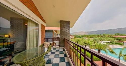 a balcony with a glass table and a pool at Spree Resort Sariska in Thāna Ghāzi