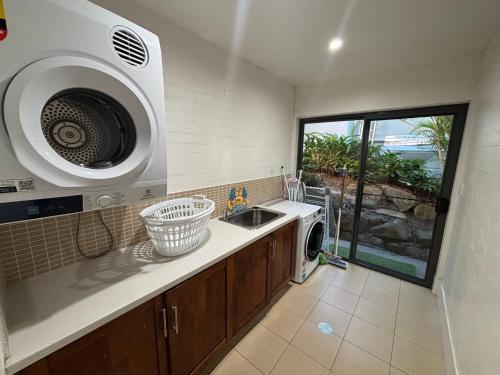 a kitchen with a sink and a washing machine at Amaroo - Bring your own linen in Arakoon