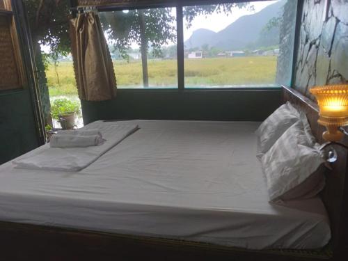a bed in a room with a large window at Tràng An Gold in Xuân Sơn