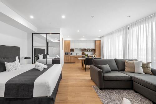 a bedroom with a bed and a couch and a kitchen at Kove Apartment - G06 in Kiama