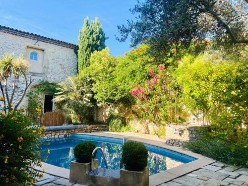 a swimming pool in front of a house with flowers at La Maison Des Autres, piscine chauffée, chambres d'hôtes, proche d'Uzès, Nîmes, Pont du Gard, Alès in Saint-Géniès-de-Malgoirès