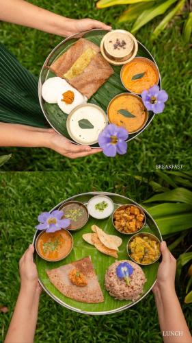 a person holding a tray of food on a plate at Mango Orchards Two in Auroville