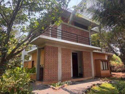 a brick house with a balcony on top of it at Mango Orchards Two in Auroville