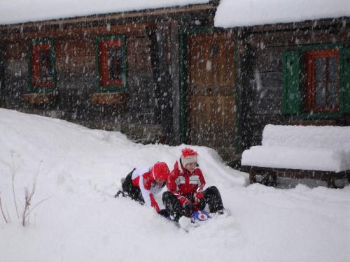 a child is sitting in the snow at Haus Speck`n in Ranten