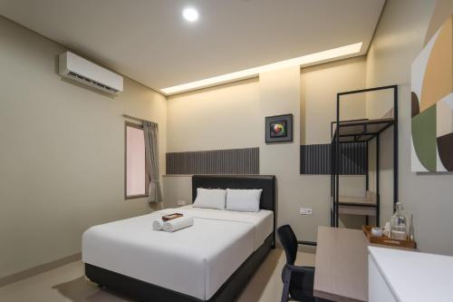 a bedroom with a white bed and a desk and a chair at Cove Juanda One in Jakarta