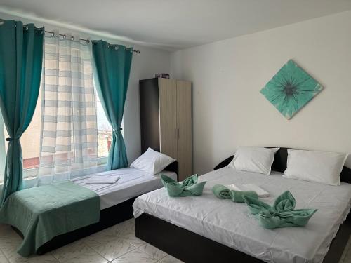 two beds in a room with blue curtains and a window at Hotel Zora by TM in Ravda