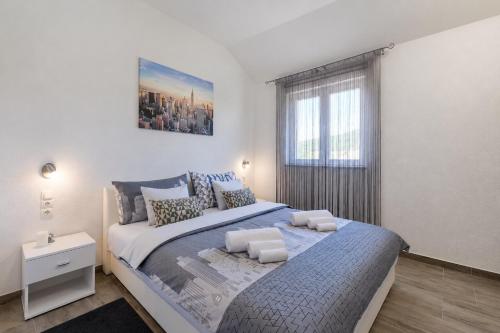 a white bedroom with a large bed and a window at Apartments Ana in Gornji Karin