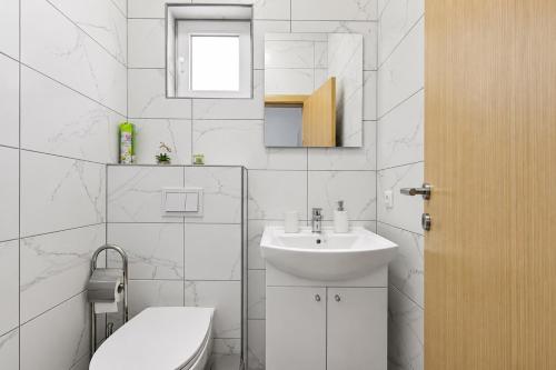 a white bathroom with a sink and a toilet at Apartments Ana in Gornji Karin