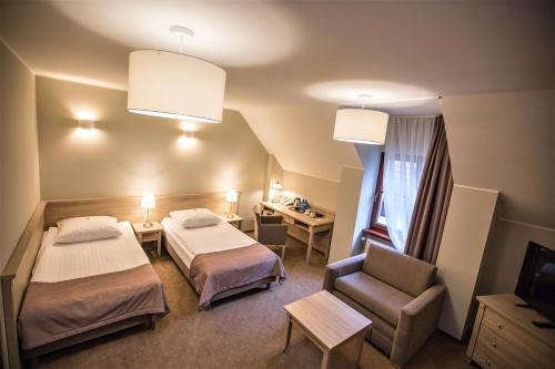 une chambre d'hôtel avec deux lits et une chaise dans l'établissement Zajazd Pod Szyszkami, à Krotoszyn