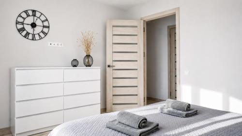 a bedroom with a bed and a dresser and a clock at K-49 prie Jūros in Klaipėda