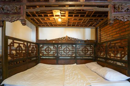 a bedroom with a wooden bed with white sheets at Griya Gribig Guest House Mitra RedDoorz in Malang