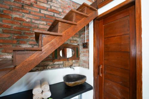 a bathroom with a wooden staircase and a sink at Griya Gribig Guest House Mitra RedDoorz in Malang