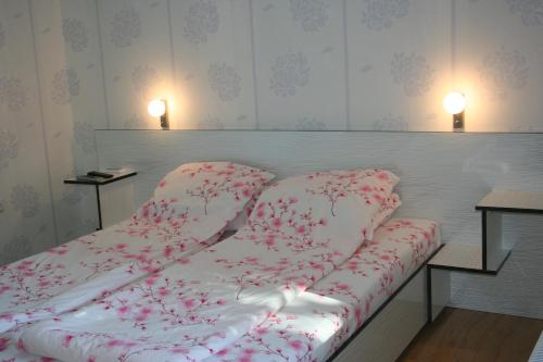 a bed in a room with red flowers on it at Bolyarski Stan Guest House in Veliki Preslav